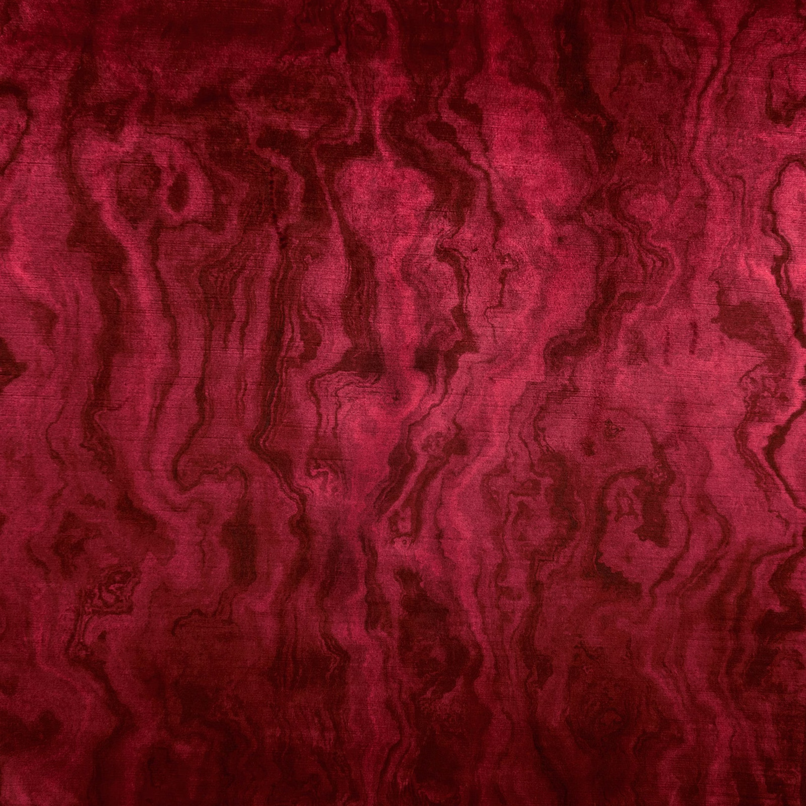 Close view of deep ruby-red cloth with flowing dark wine marbling