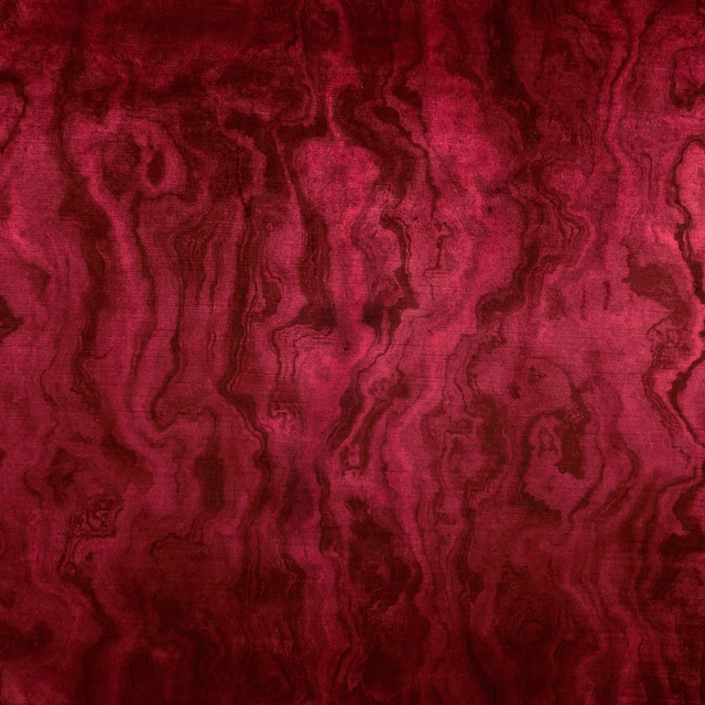 Close view of deep ruby-red cloth with flowing dark wine marbling