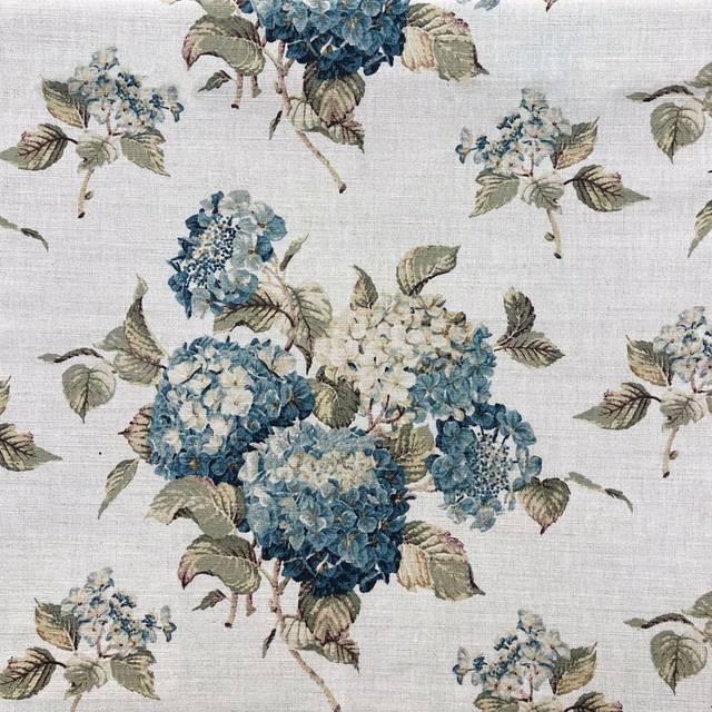 Cool blue hydrangea clusters with sage leaves on a pale linen-look ground