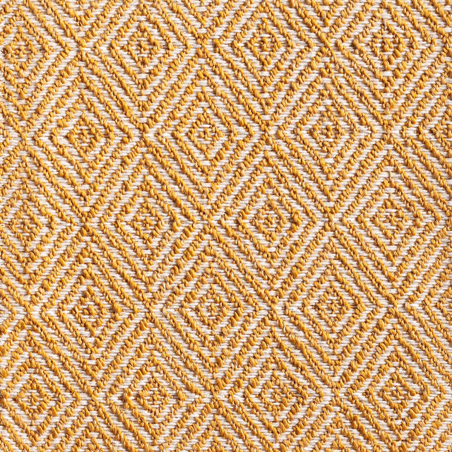 Turmeric and cream woven fabric with raised repeating diamond motifs and tactile diagonal yarns