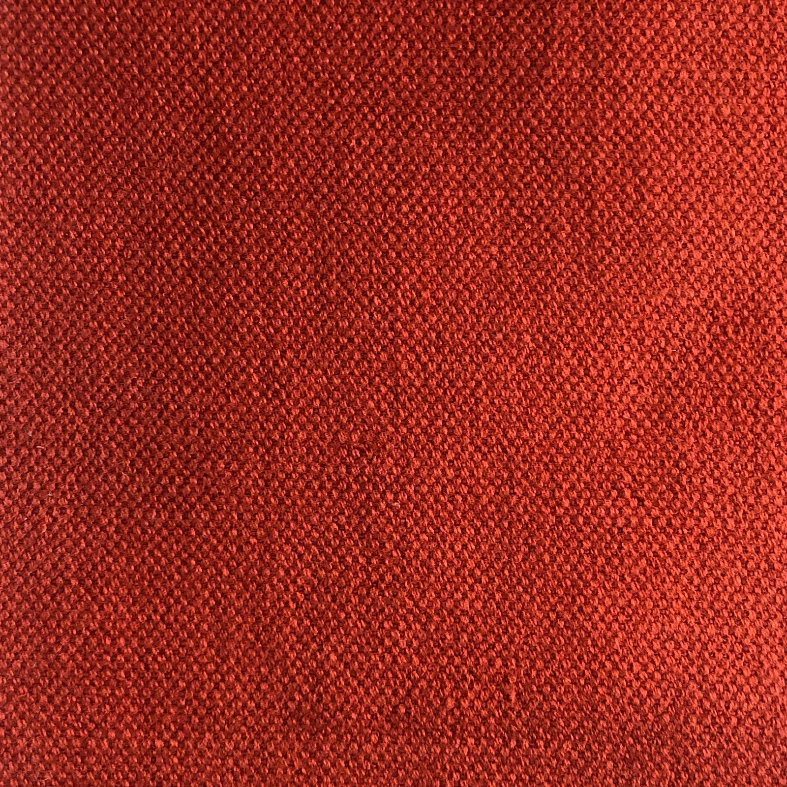 Close-up of dense terracotta-red woven fabric with fine tonal texture