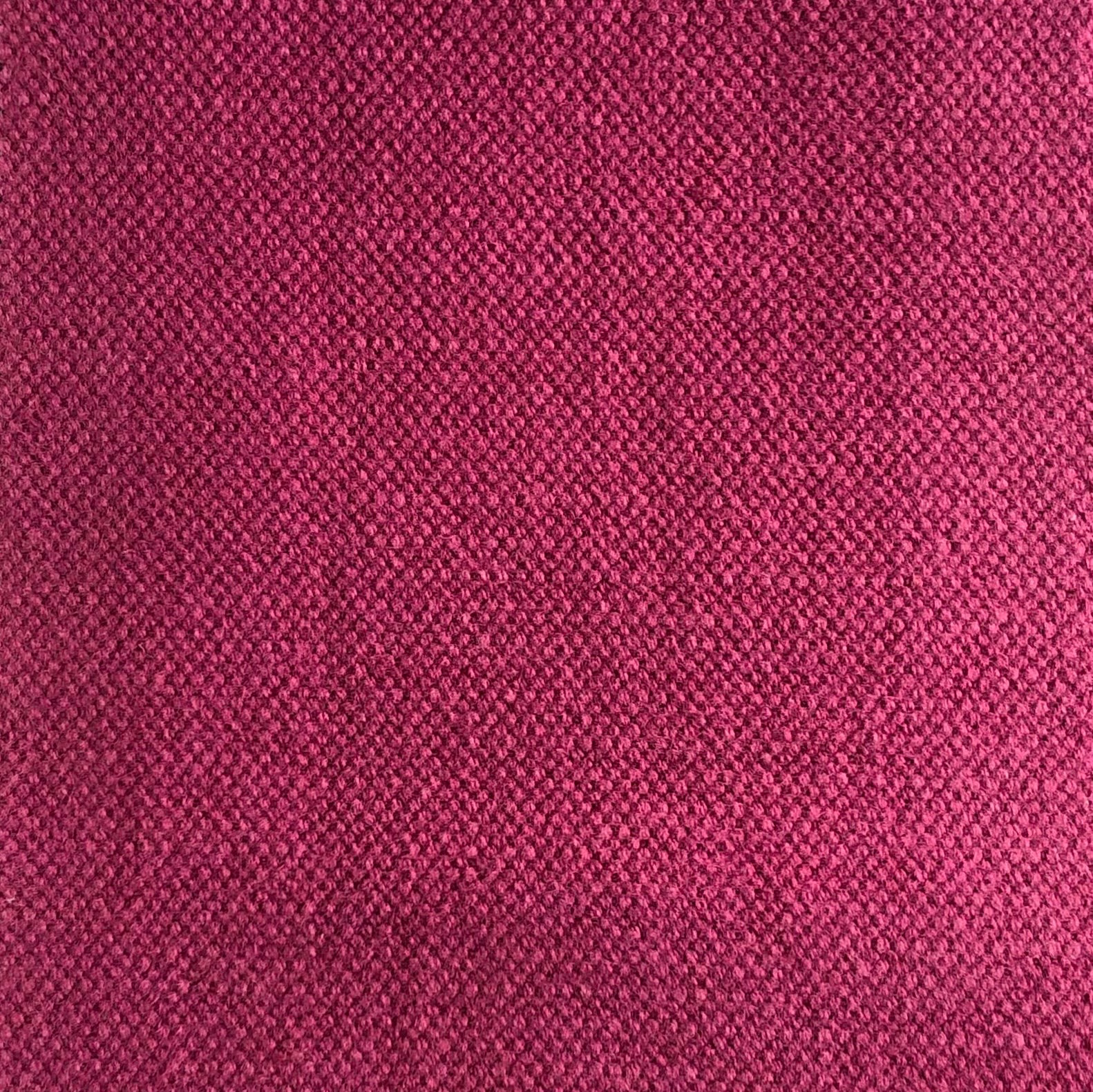 Close-up of dense raspberry pink woven fabric with fine wine-toned texture