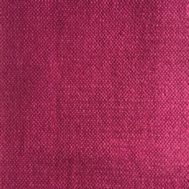 Close-up of dense raspberry pink woven fabric with fine wine-toned texture