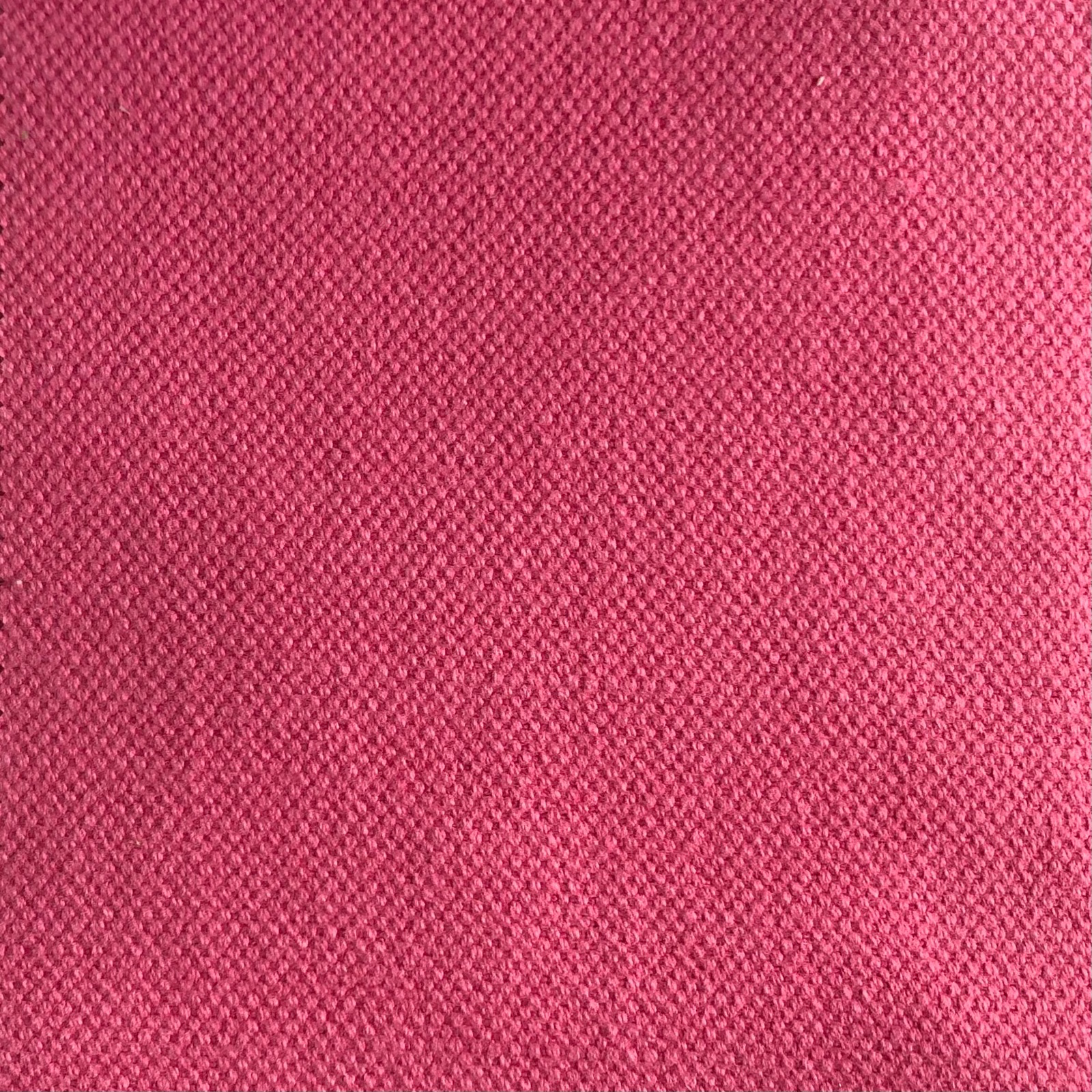 Close-up of deep raspberry pink fabric with a fine, subtly variegated woven texture