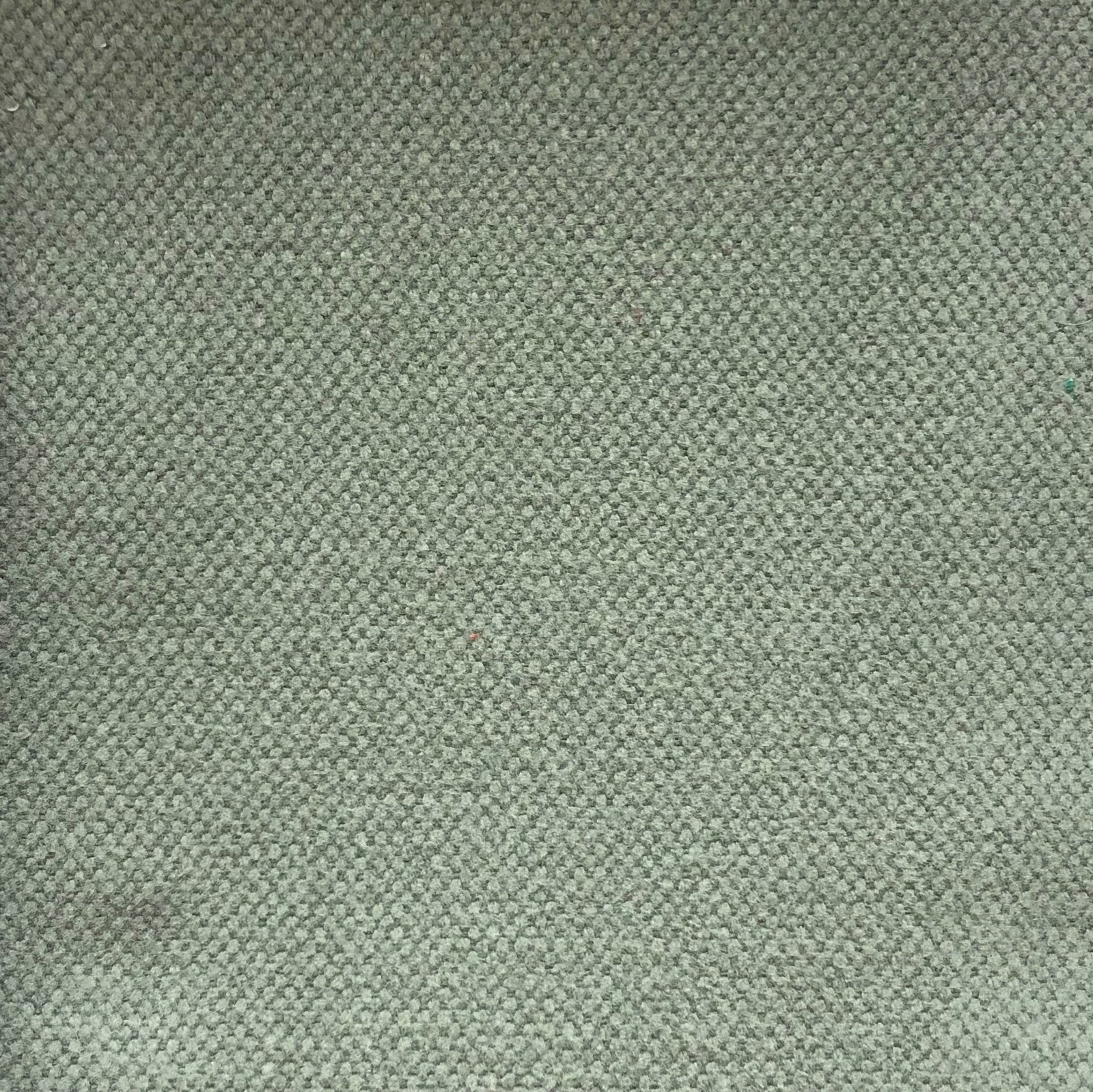Close-up of muted sage-grey fabric with a dense, finely pebbled woven texture