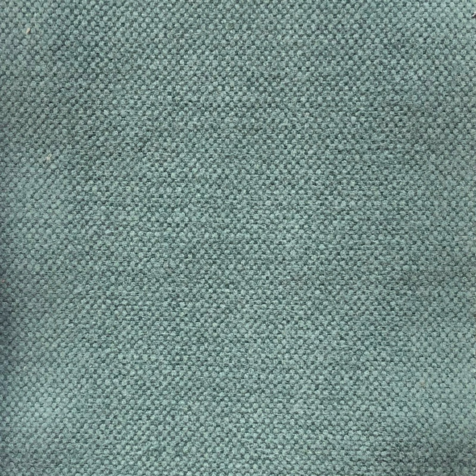 Close-up of muted teal-blue fabric with a dense, softly pebbled woven texture