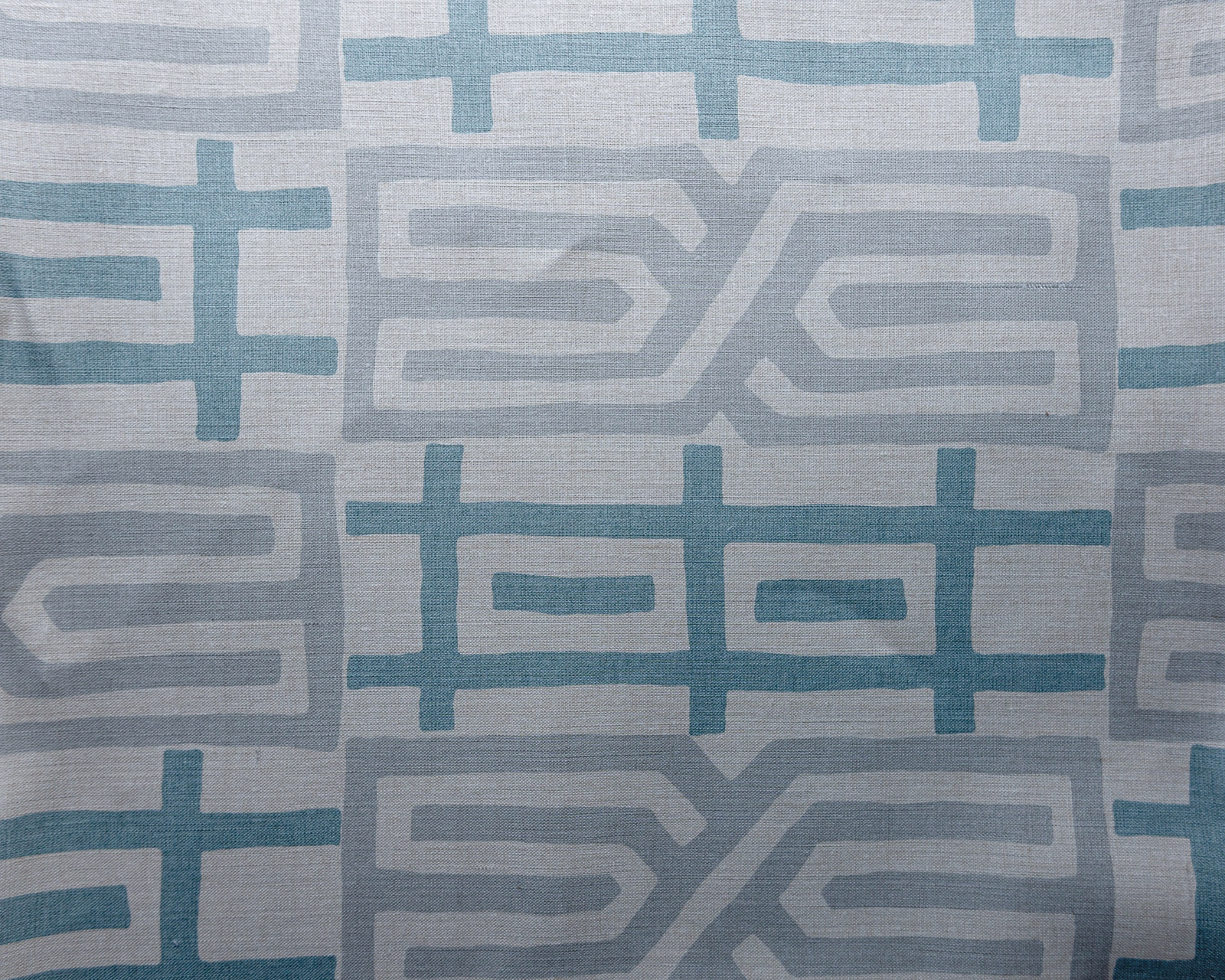 Swatch of geometric teal, grey and white woven fabric with large pattern