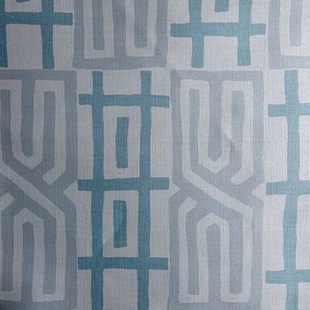 Swatch of geometric teal, grey and white woven fabric with large pattern