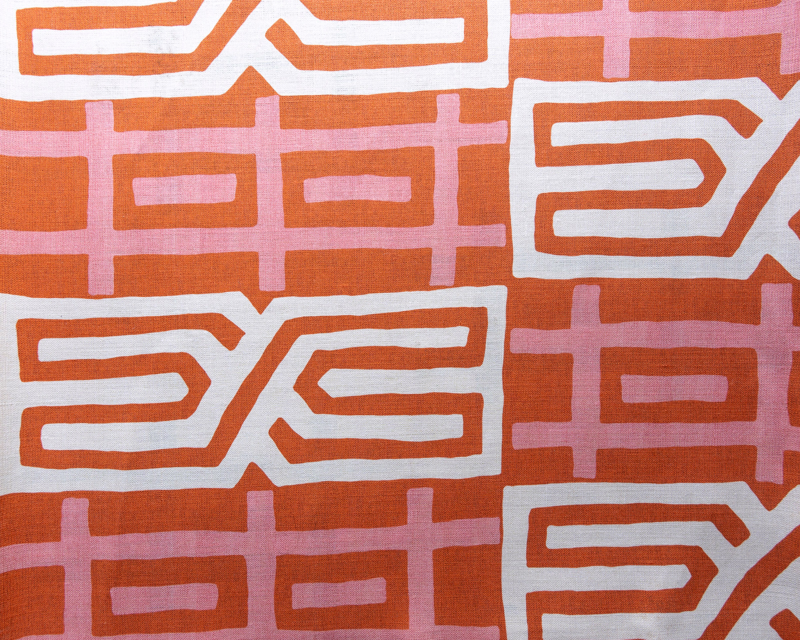 Coral orange geometric fabric swatch with white and blush pink motifs
