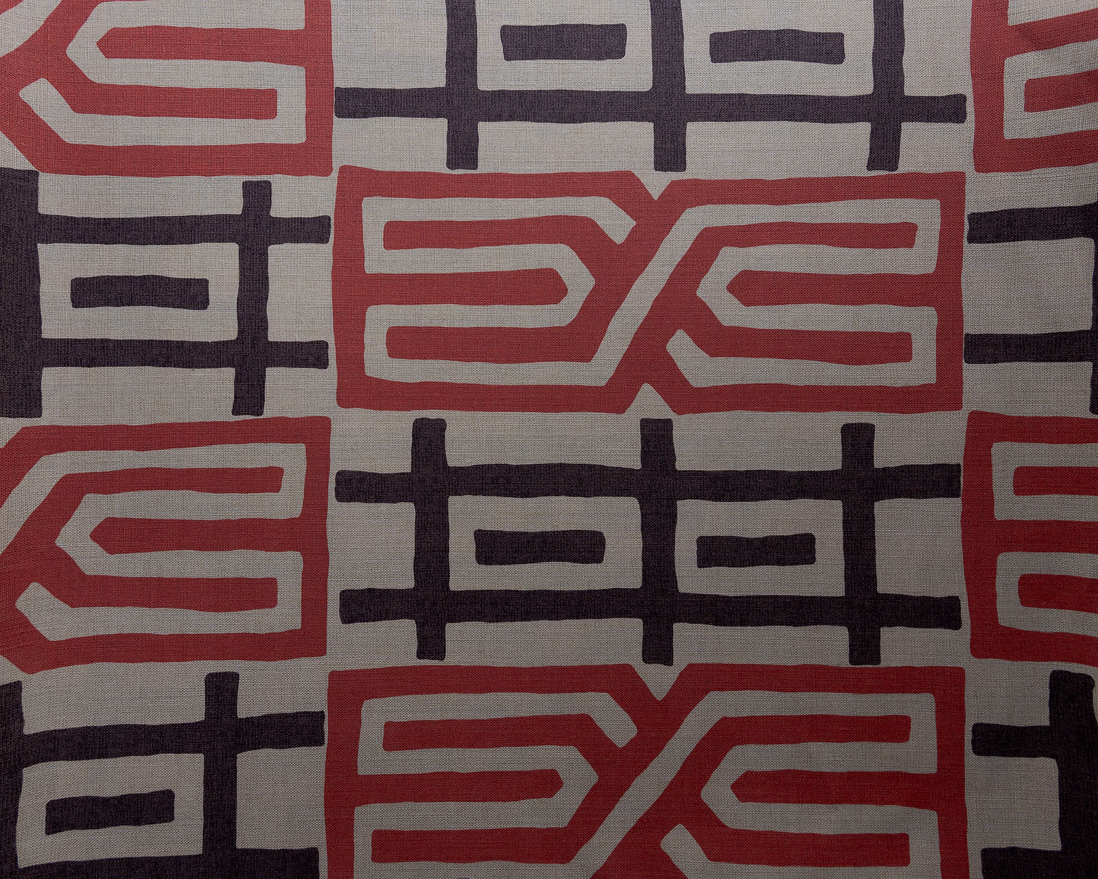Large coral red and charcoal geometric Kuba pattern on a pale textured fabric