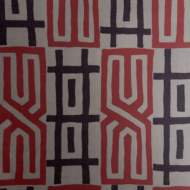 Large coral red and charcoal geometric Kuba pattern on a pale textured fabric
