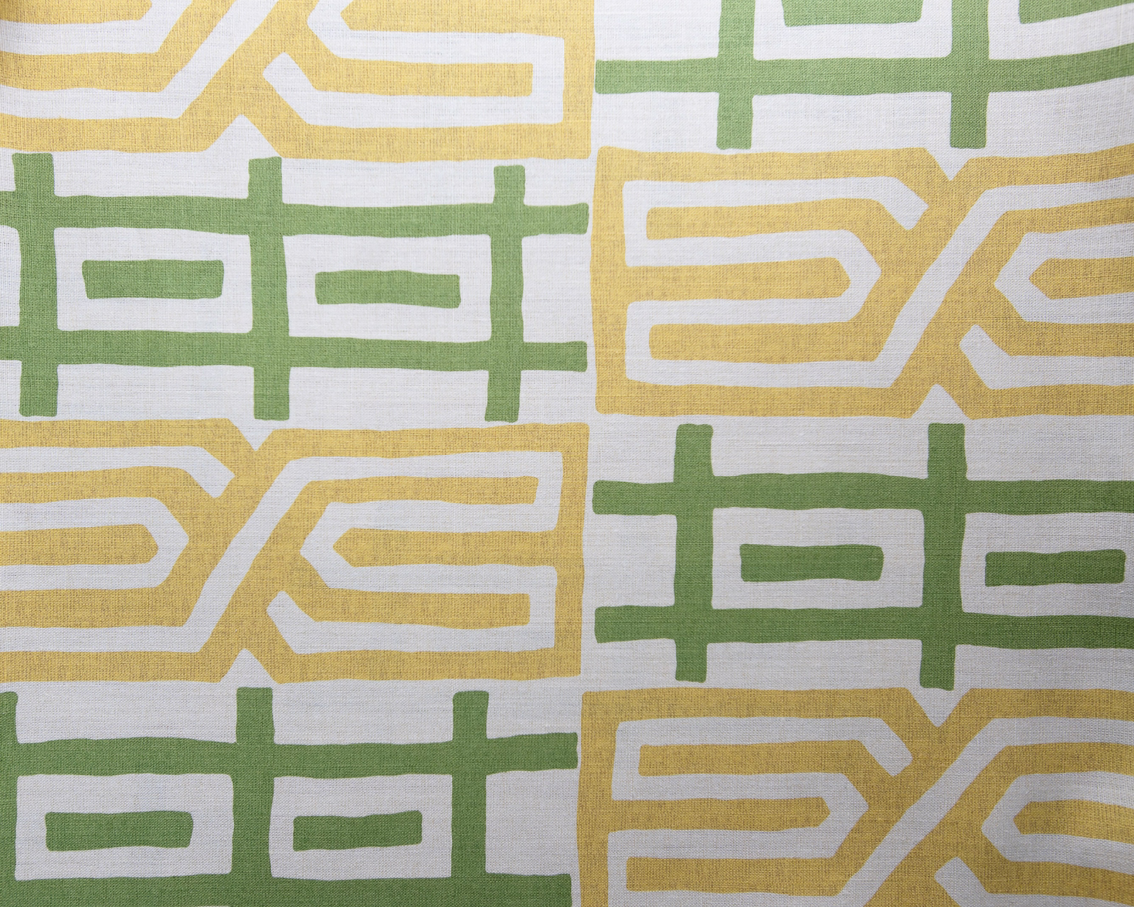 Large geometric fabric swatch in sage green and buttery yellow on a pale ground