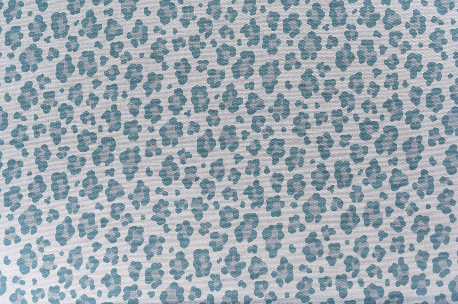 Pale fabric swatch with small aqua leopard spots on a light ground