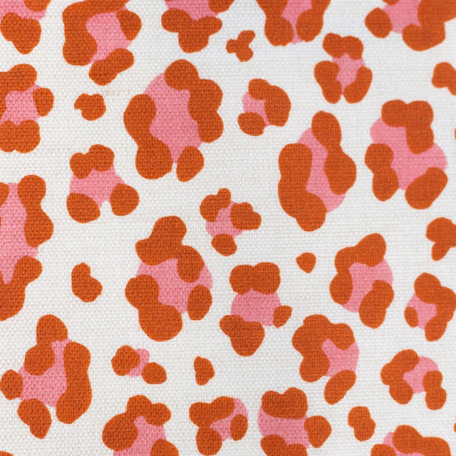 Coral orange and pink leopard spot pattern on pale woven fabric