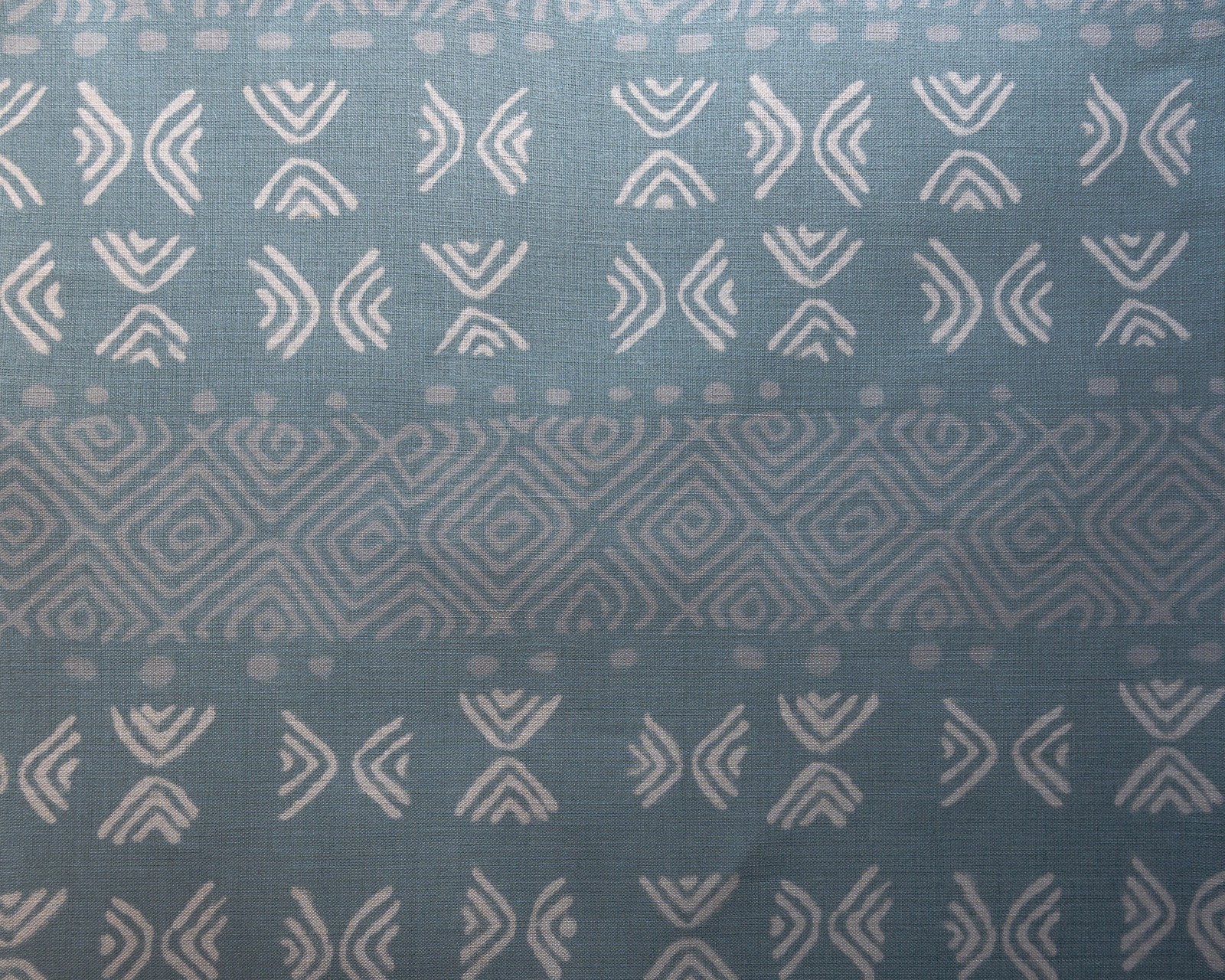 Soft blue geometric patterned fabric with pale motifs and a central stripe