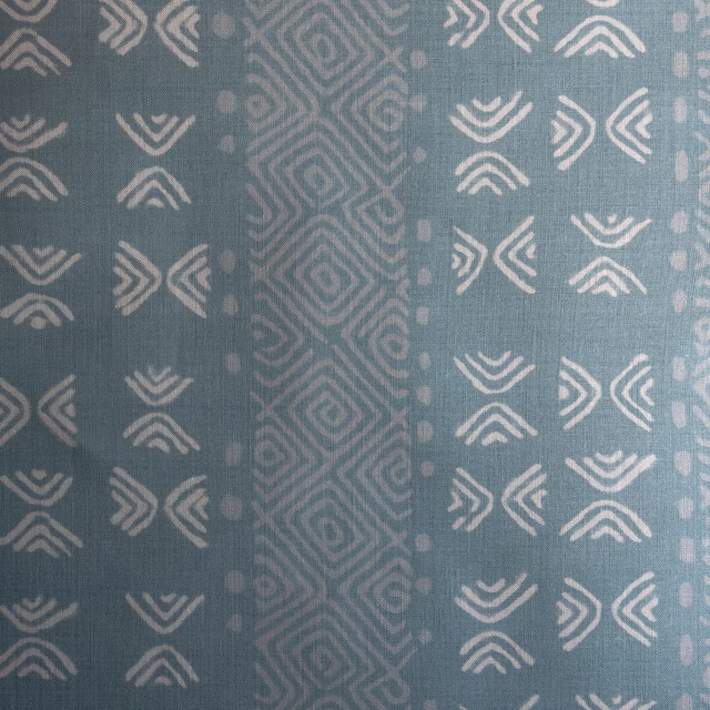 Soft blue geometric patterned fabric with pale motifs and a central stripe