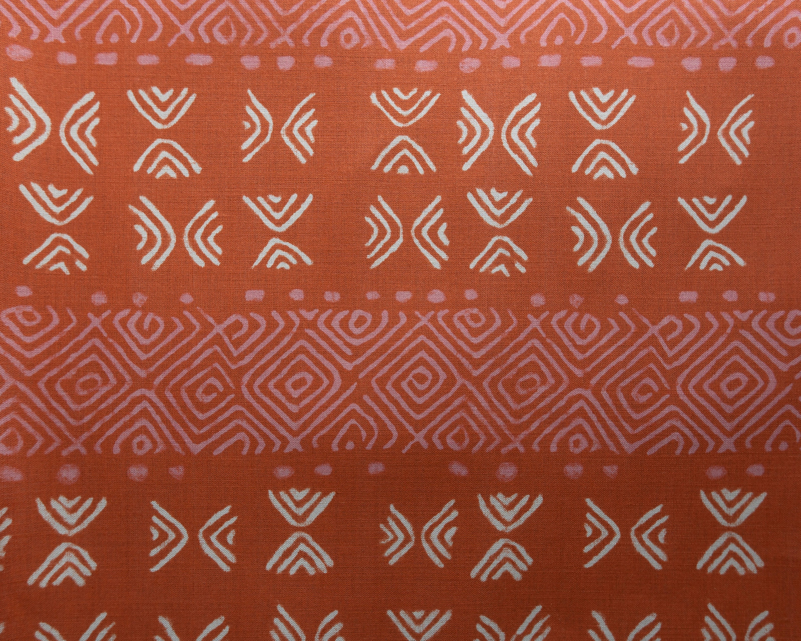 Terracotta orange fabric with ivory geometric motifs and a pink patterned stripe