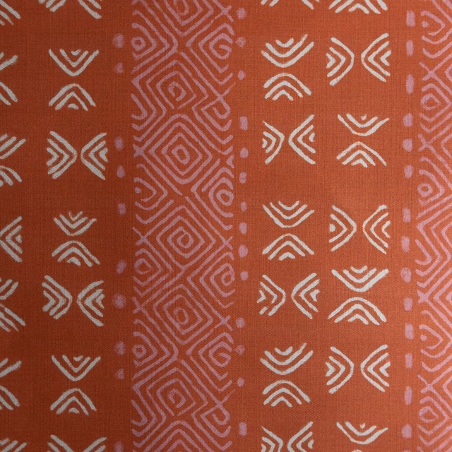 Terracotta orange fabric with ivory geometric motifs and a pink patterned stripe