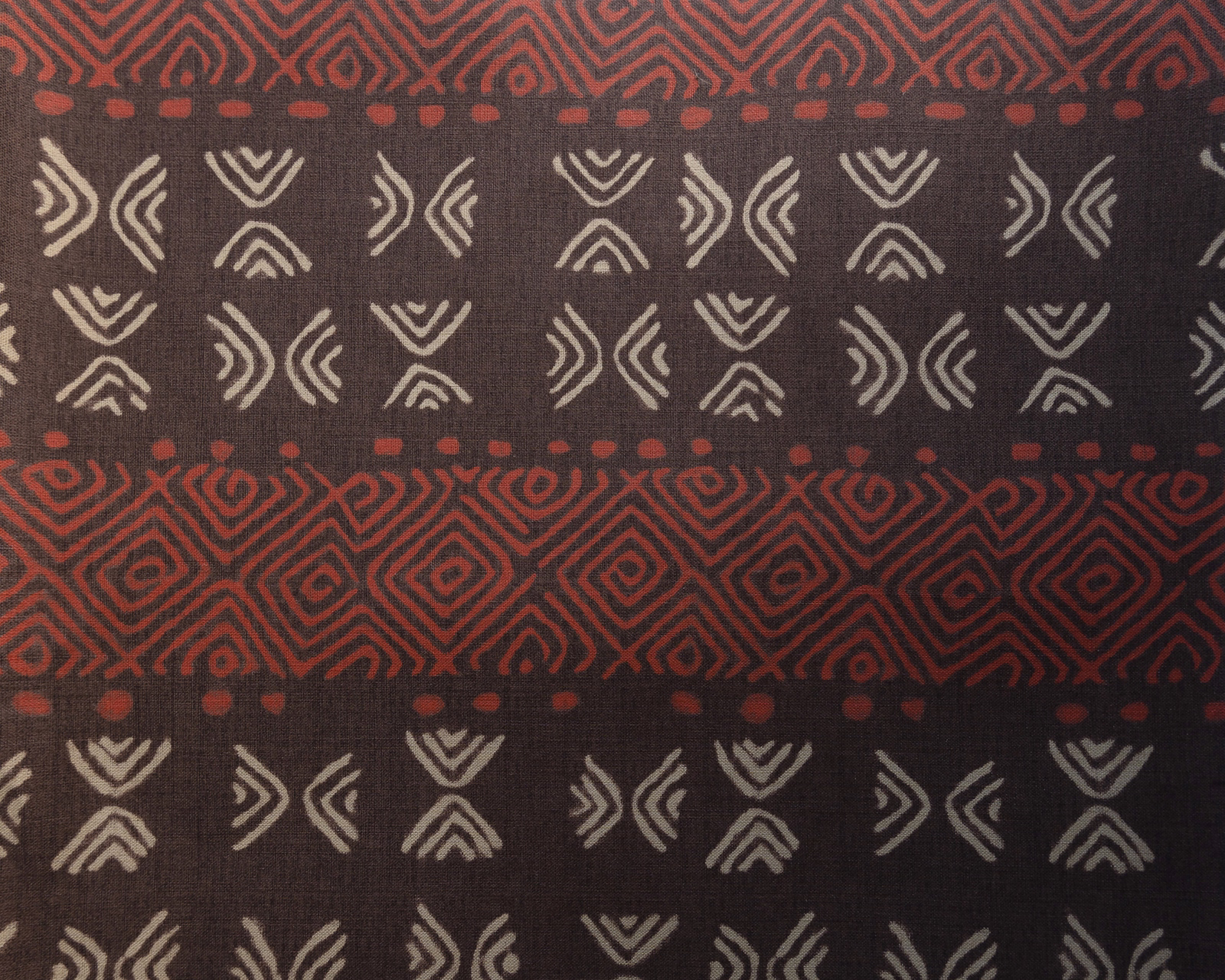 Dark brown patterned fabric with rust red vertical geometric bands and ivory motifs