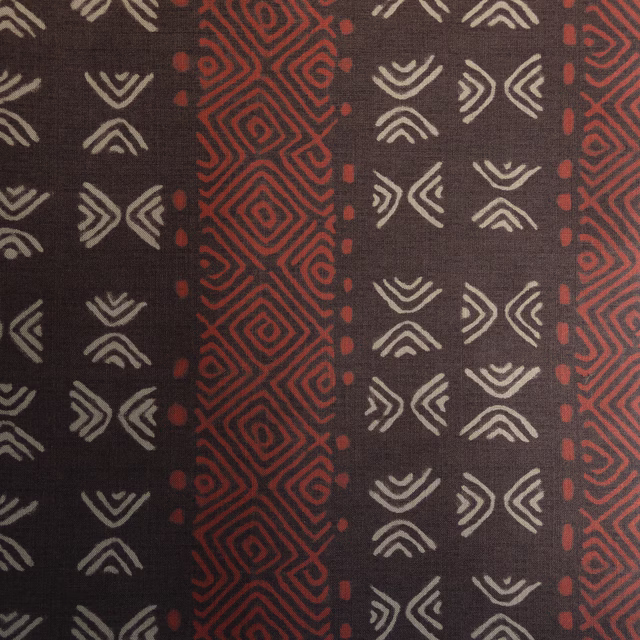 Dark brown patterned fabric with rust red vertical geometric bands and ivory motifs