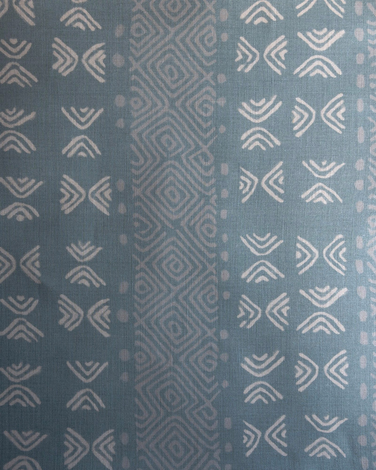 Blue-green geometric fabric swatch with pale chevrons and diamond stripes