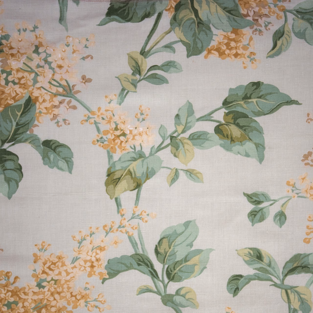Celadon floral fabric with green leaves and pale peach blossom on a linen-look ground
