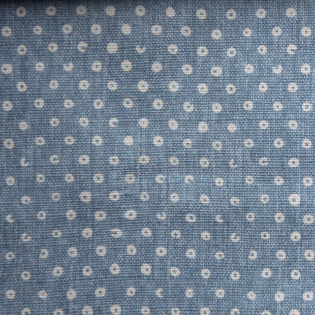 Blue woven fabric with tiny ivory ring spots on a textured ground