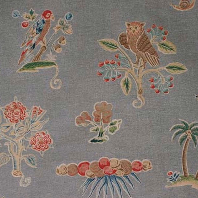 Blue-grey fabric swatch with scattered embroidered-style birds, flowers and trees