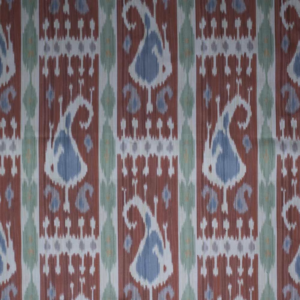 Rust-red ikat fabric with pale blue teardrop motifs and green vertical accents