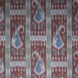 Rust-red ikat fabric with pale blue teardrop motifs and green vertical accents