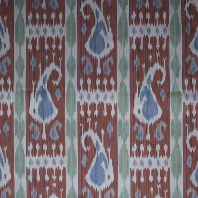 Rust-red ikat fabric with pale blue teardrop motifs and green vertical accents