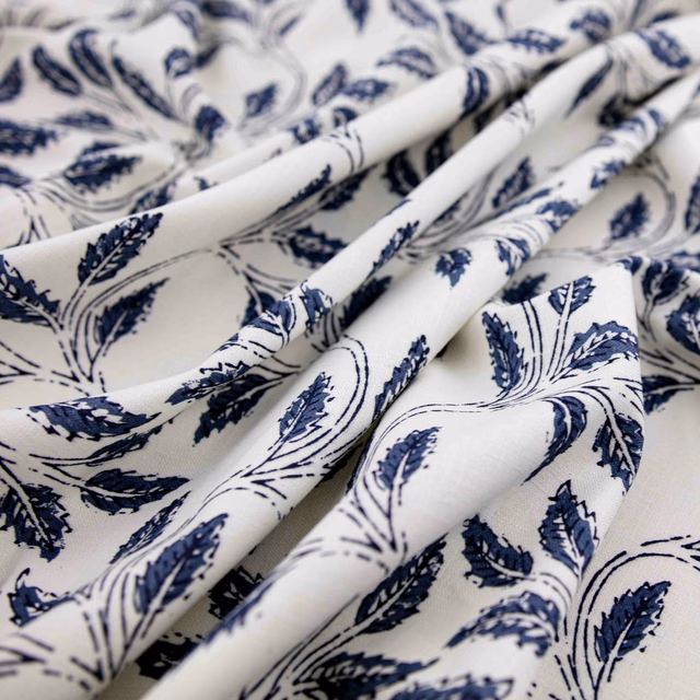 Cream fabric with crisp indigo leafy sprigs, shown in softly gathered folds