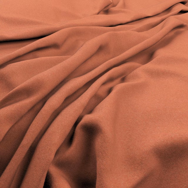 Marmalade terracotta fabric with a smooth surface arranged in softly shadowed flowing folds