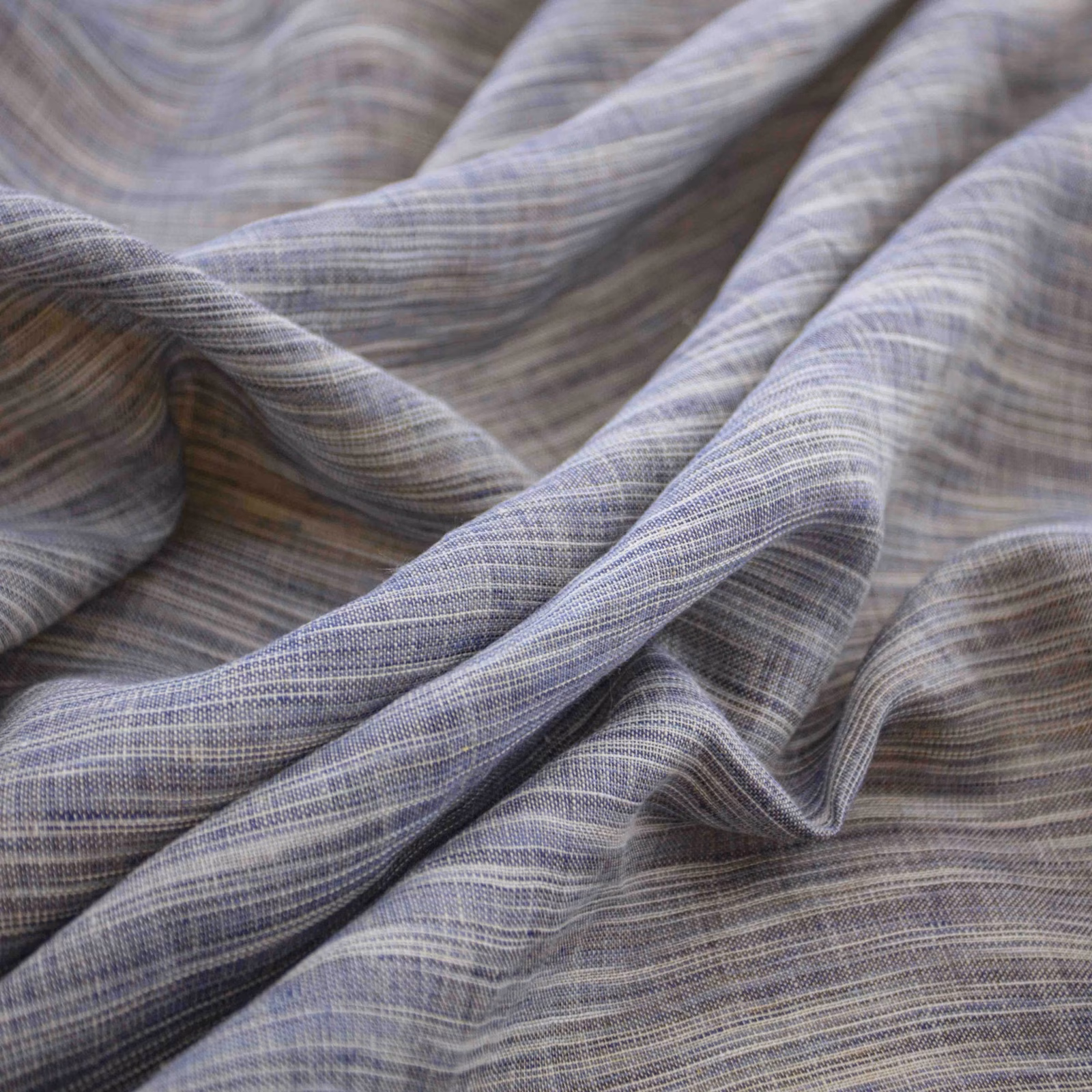 Cool ink-blue grey fabric with fine horizontal striations folded into soft, fluid drapes