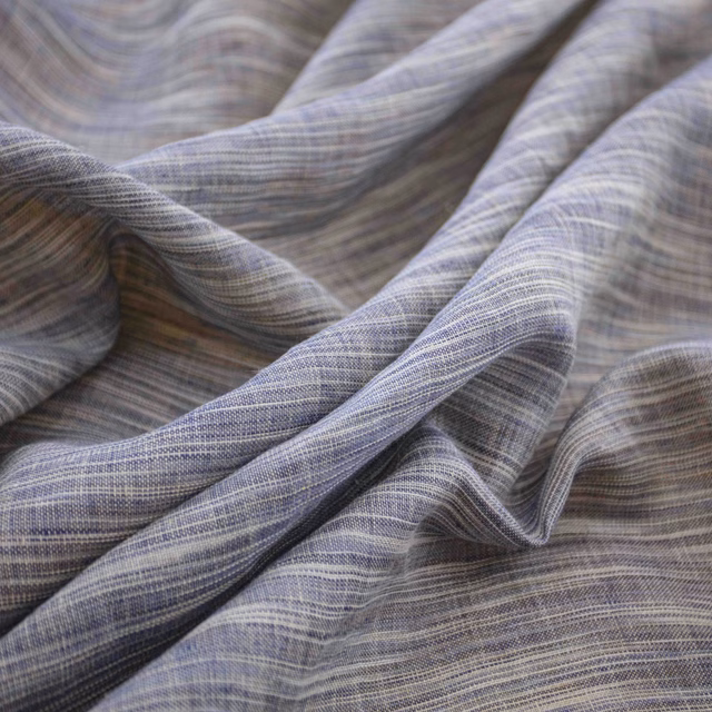 Cool ink-blue grey fabric with fine horizontal striations folded into soft, fluid drapes