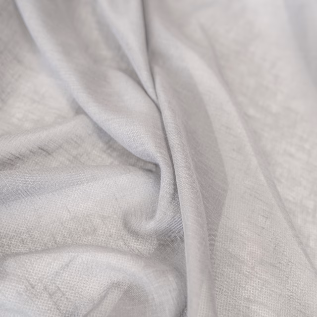 Pale ash-grey finely woven textile draped in soft folds with subtle tonal texture