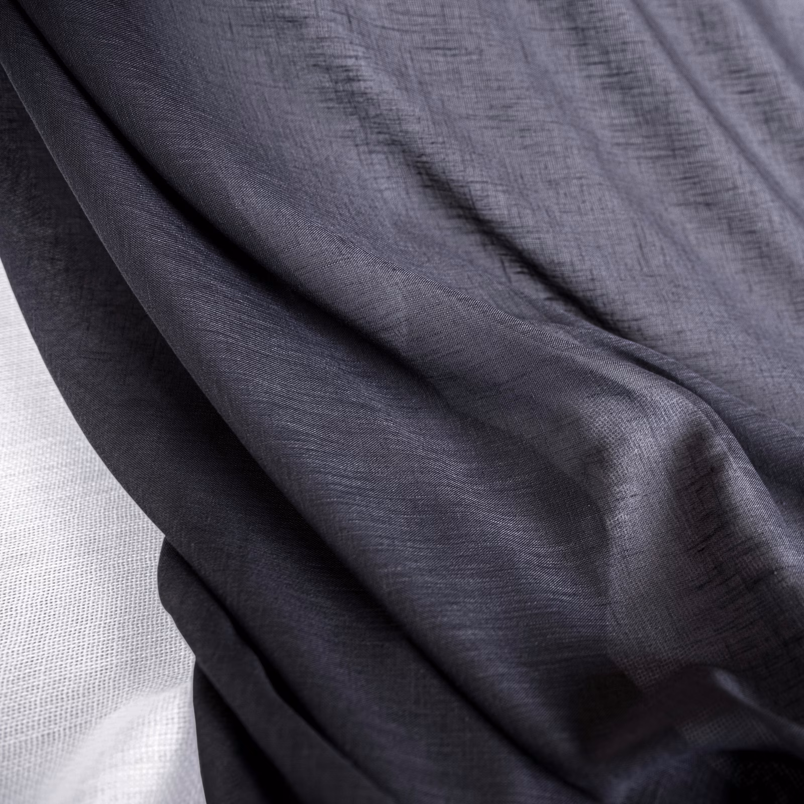 Deep charcoal grey fabric with fine crosshatched texture draped in soft folds