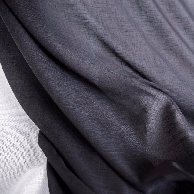 Deep charcoal grey fabric with fine crosshatched texture draped in soft folds