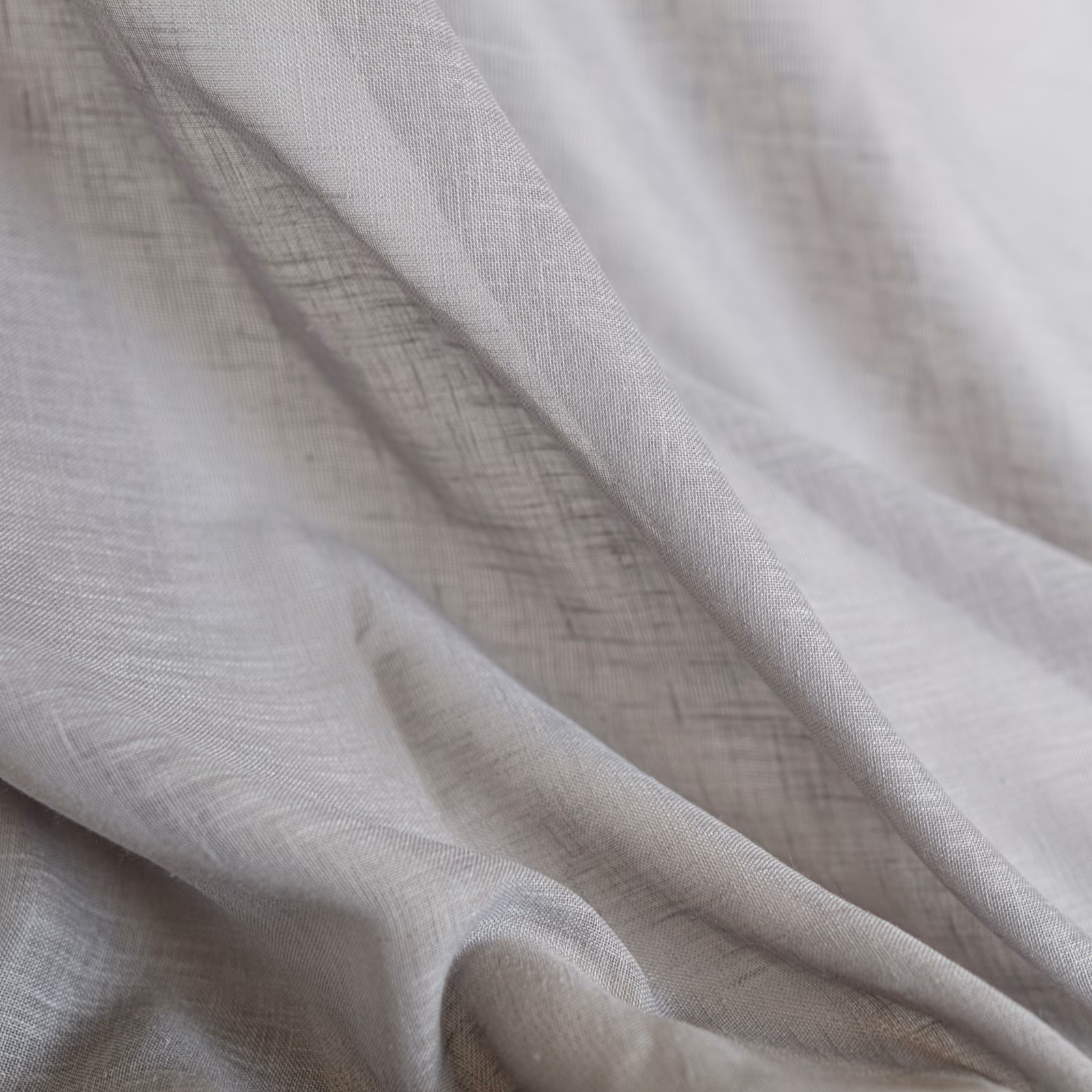Pale pebble-taupe woven textile with a fine open weave in layered folds