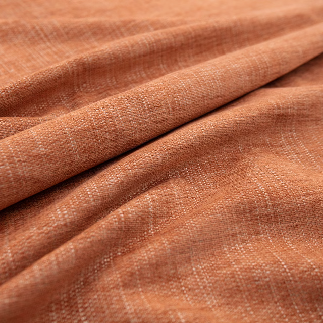 Warm henna terracotta fabric with a tactile crosshatch weave in soft folds