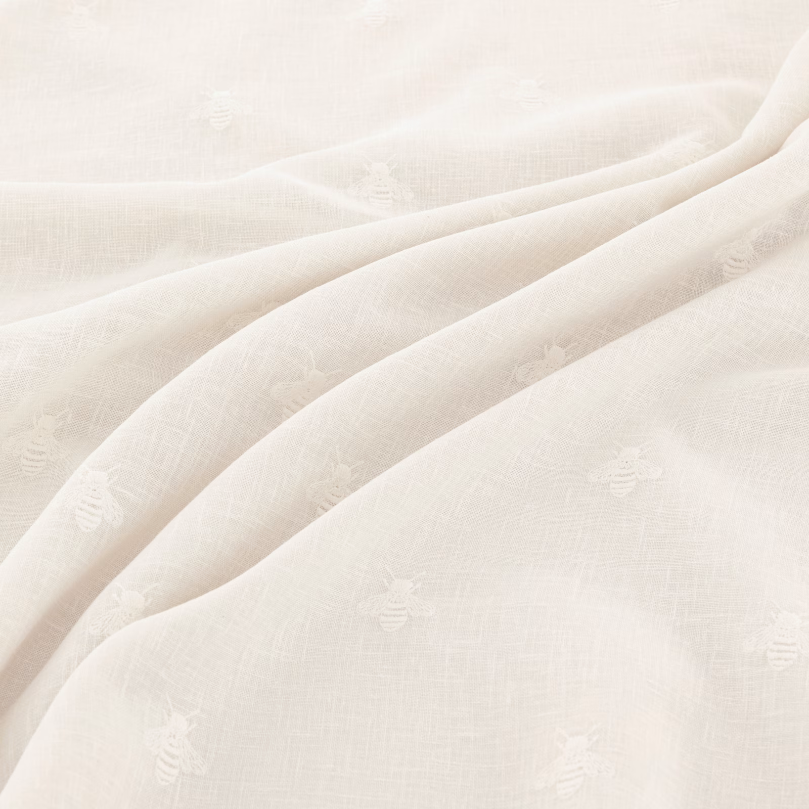 Warm ivory woven fabric with tiny tonal bee motifs and soft fluid folds