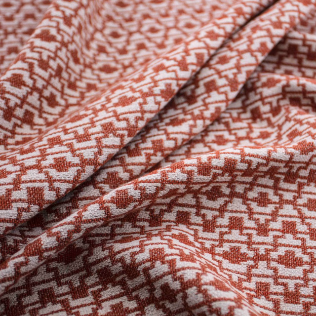 Brick-red and ivory woven geometric textile folded to reveal its textured surface