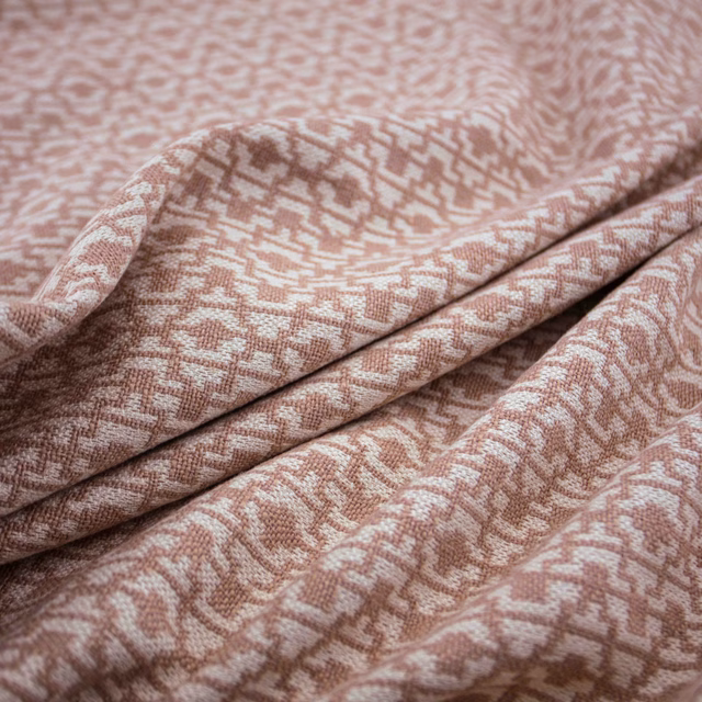 Folded muted blush-pink fabric with a small broken geometric woven motif