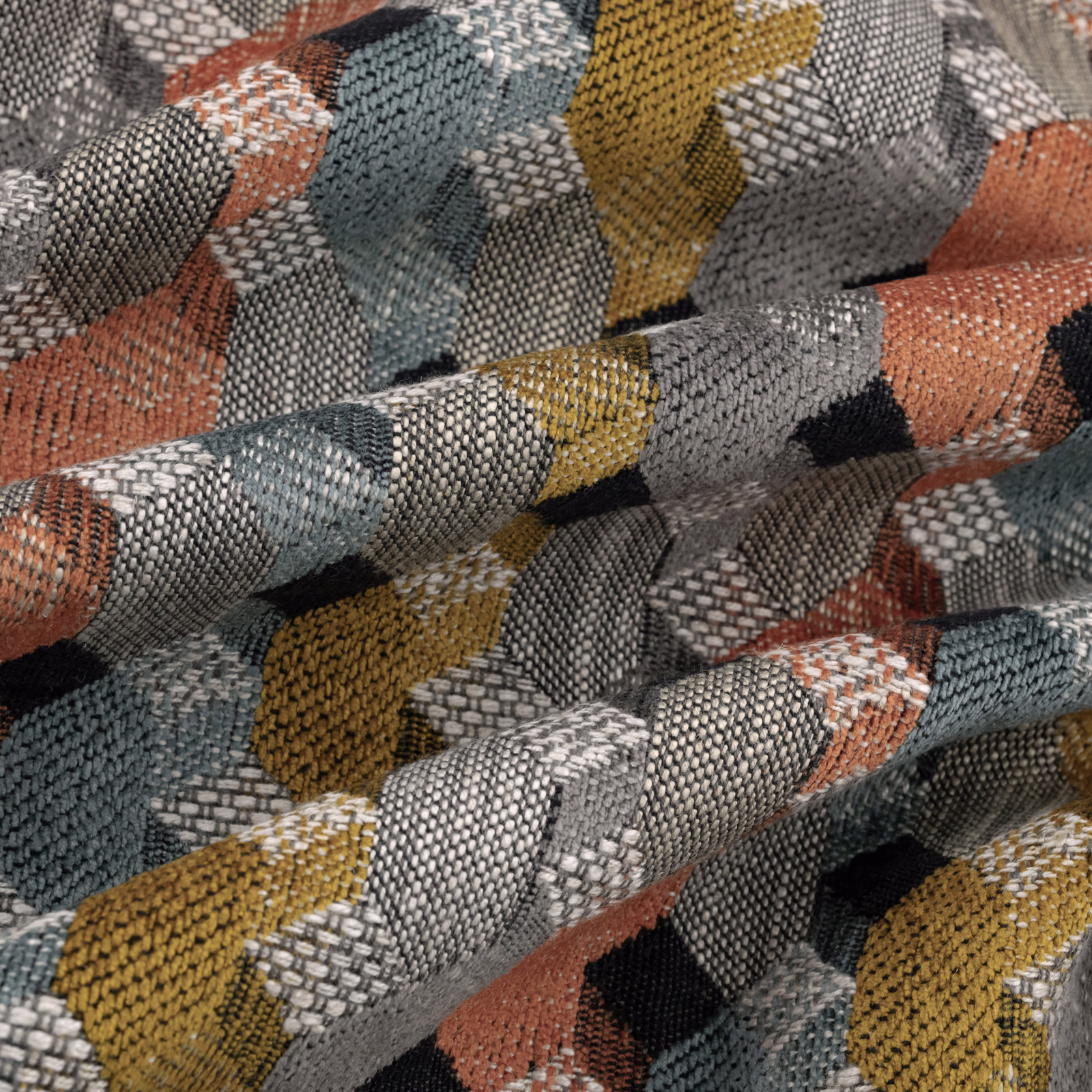 Folded geometric upholstery fabric in blue-grey, mustard, coral and black woven texture