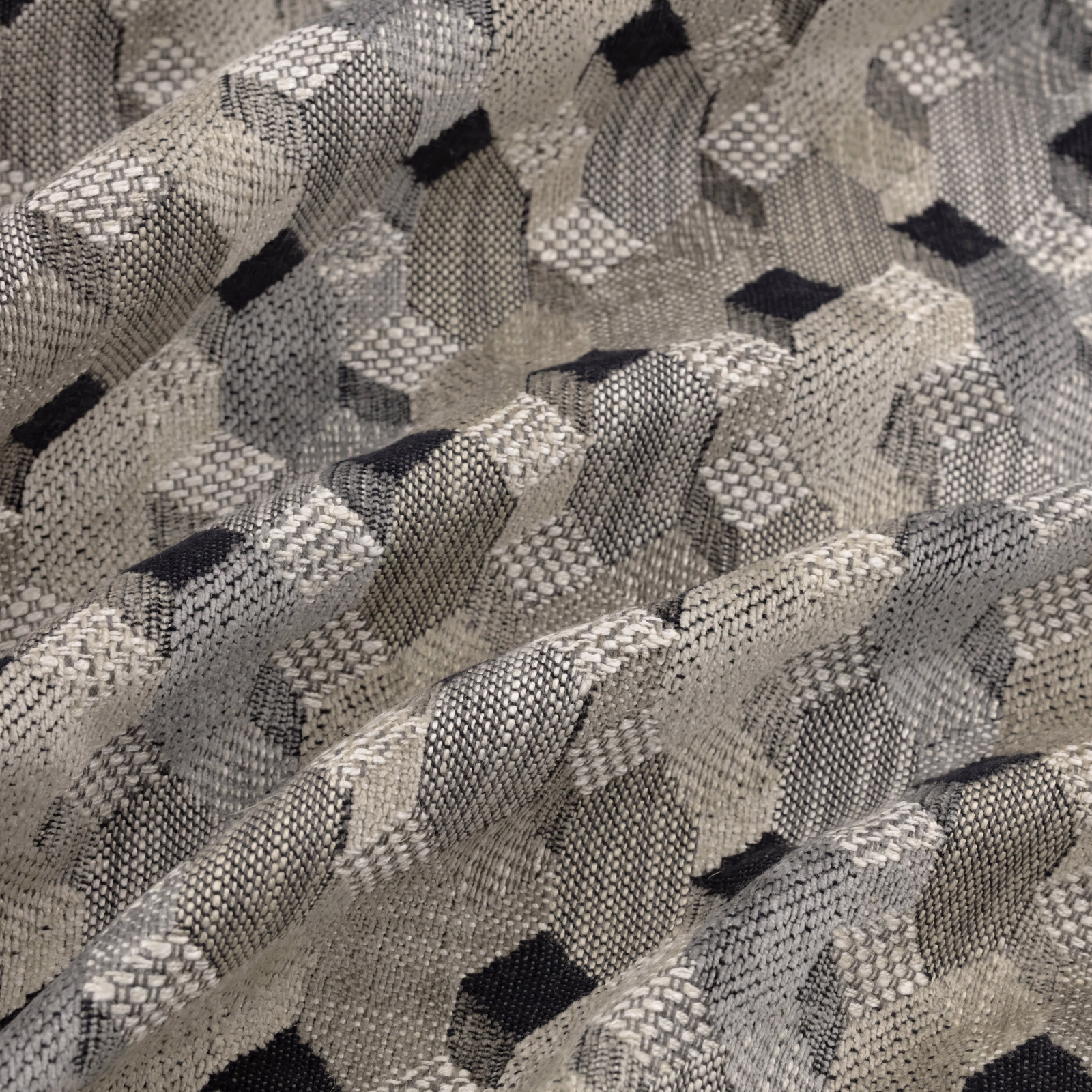 Close-up of a woven geometric fabric in soft grey, cream and charcoal tones