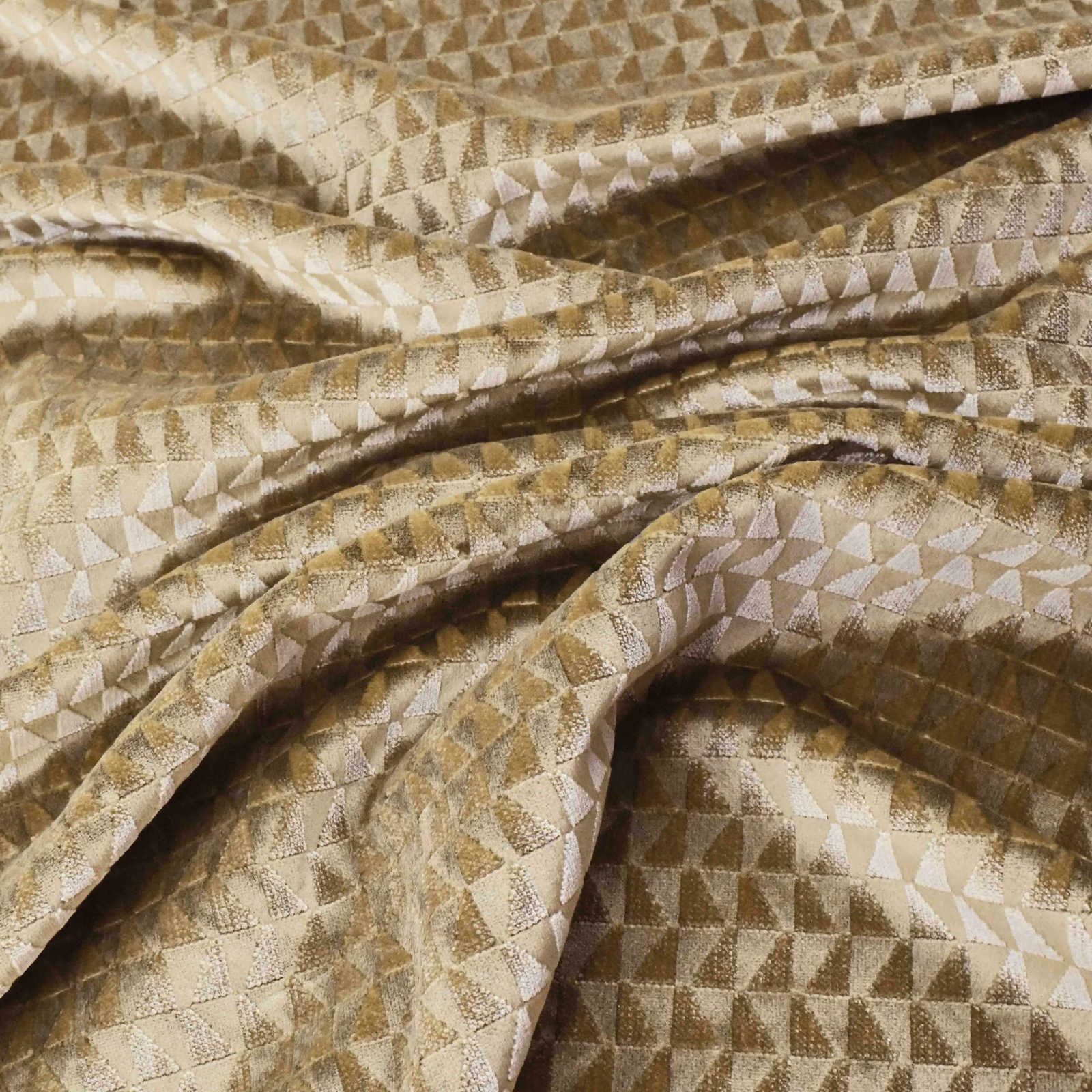 Warm gold geometric textile with ivory triangles and taupe-brown shadows in folded cloth
