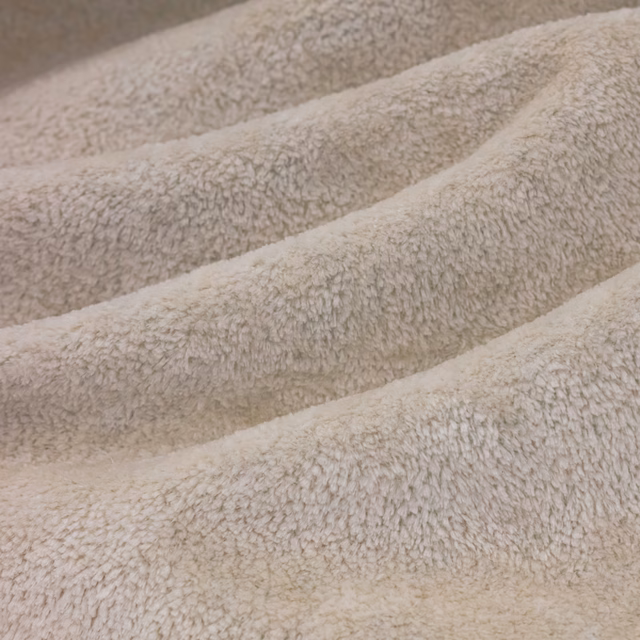 Warm chalk-cream looped pile folded into softly ridged bands