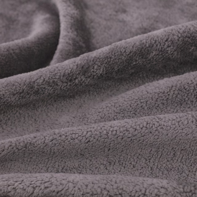 Close-up of cool chinchilla-grey fabric with dense plush nubby pile in soft folds