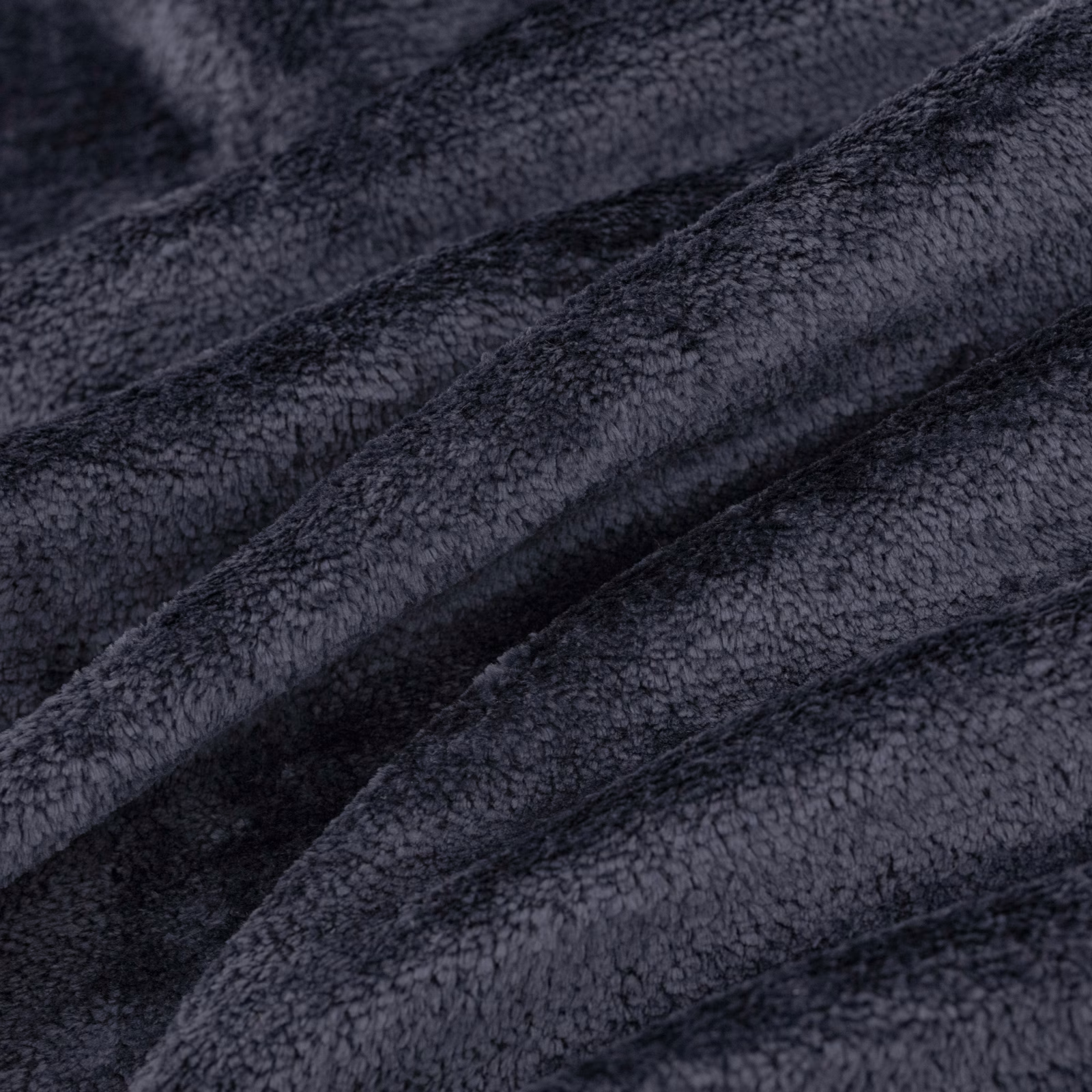 Near-black indigo fabric with dense nubby pile folded into softly shaded ridges