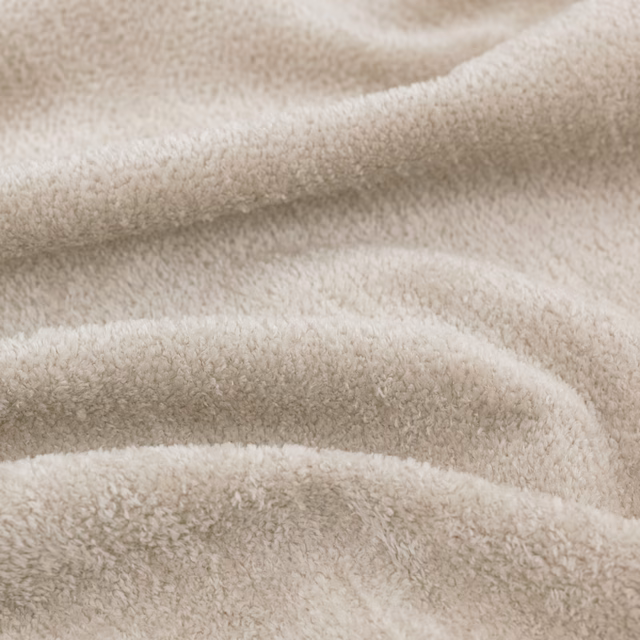 Warm ivory plush fabric with a softly napped surface in gathered folds